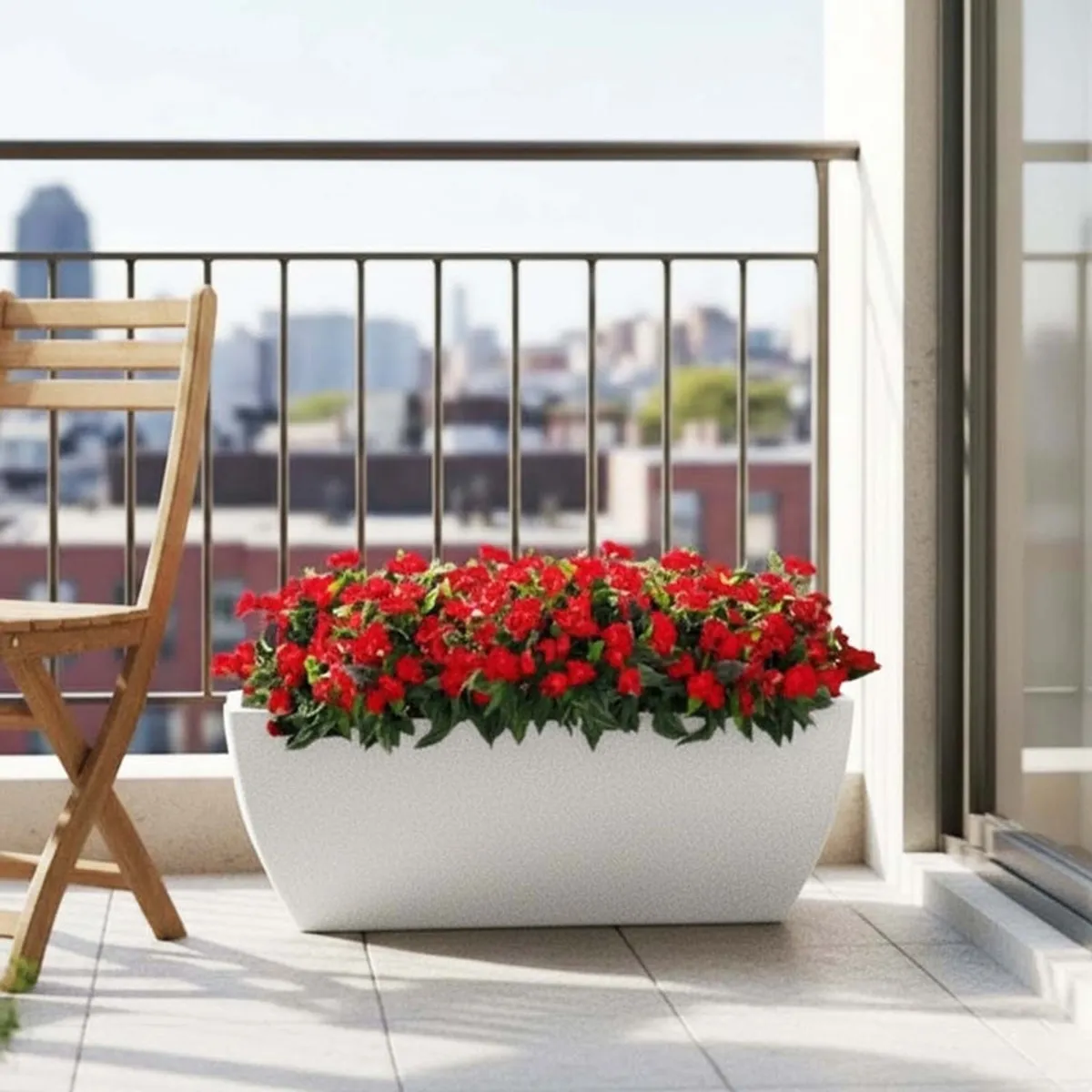 White rectangular planter filled with red flowers on a sunny balcony.
