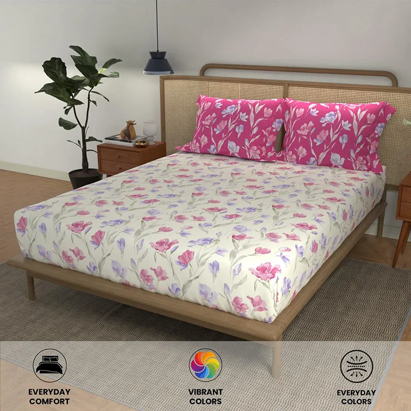 Cream floral bedsheet with bright pink floral pillow covers on a bed