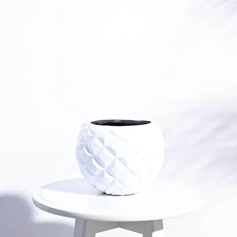 White faceted planter shown empty on a round white table.