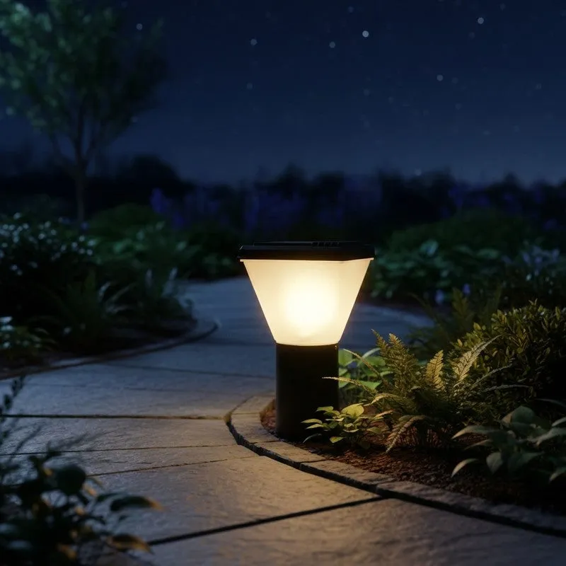 Black and white outdoor lamp glowing beside a garden pathway at night