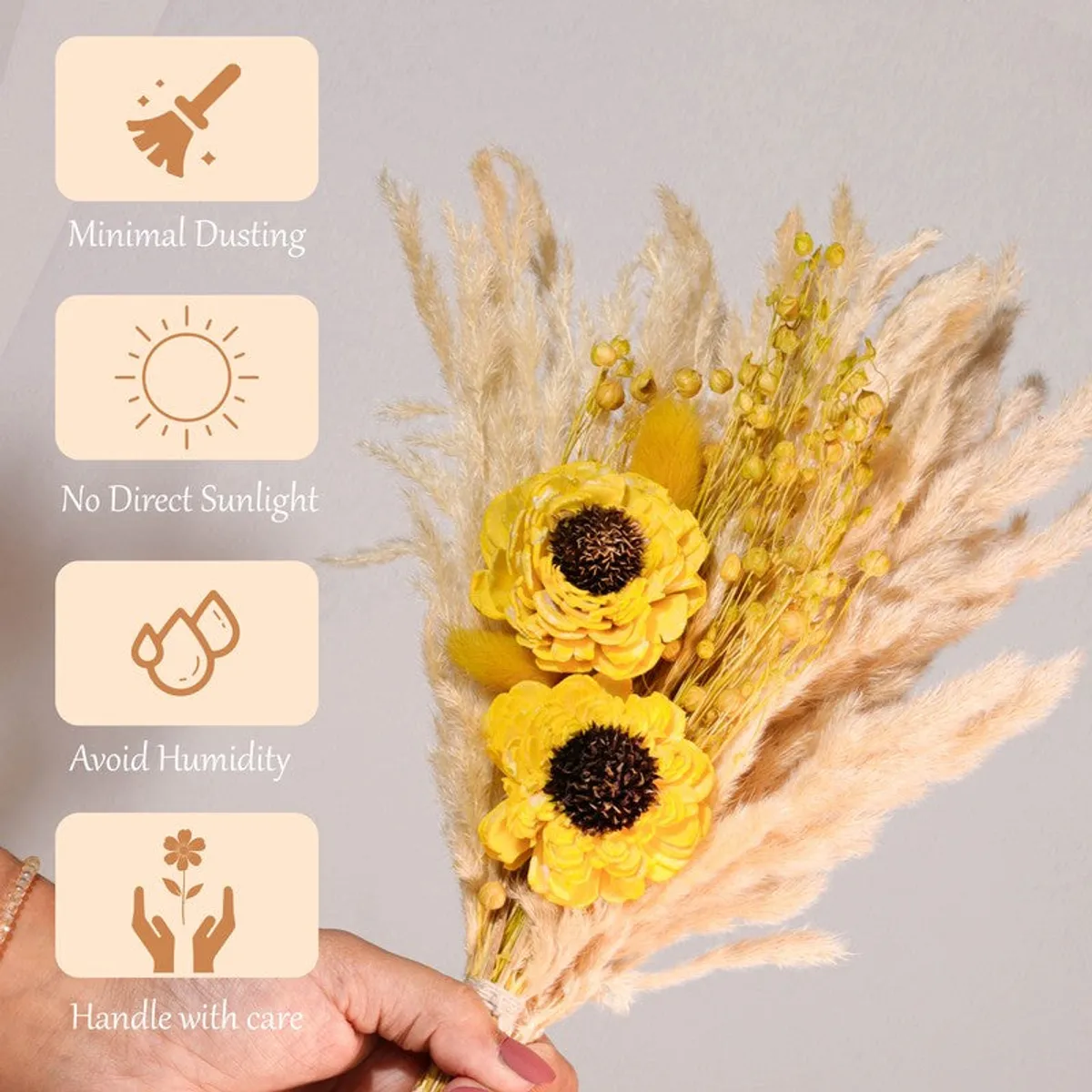 Yellow dried flower bunch held by hand, showing fluffy pampas grass and dried blooms