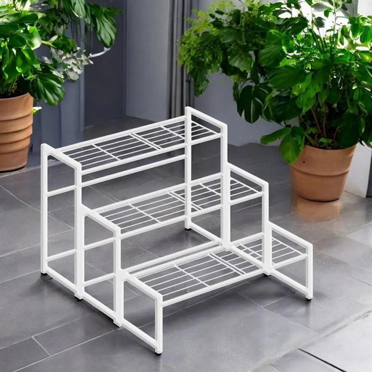 White stepped planter stand shown empty among indoor plants