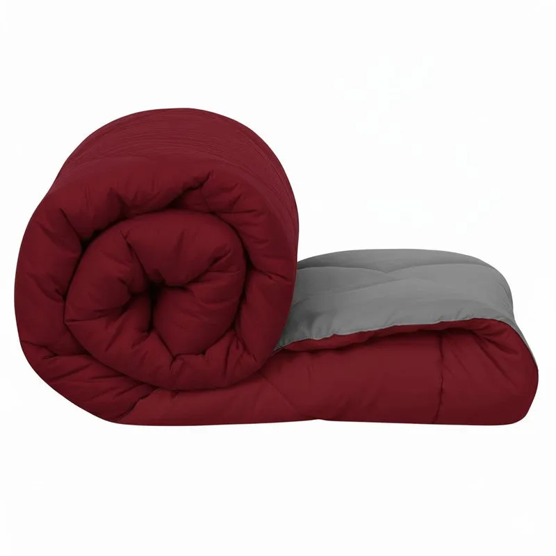 Rolled maroon and grey reversible comforter showing its quilted layers