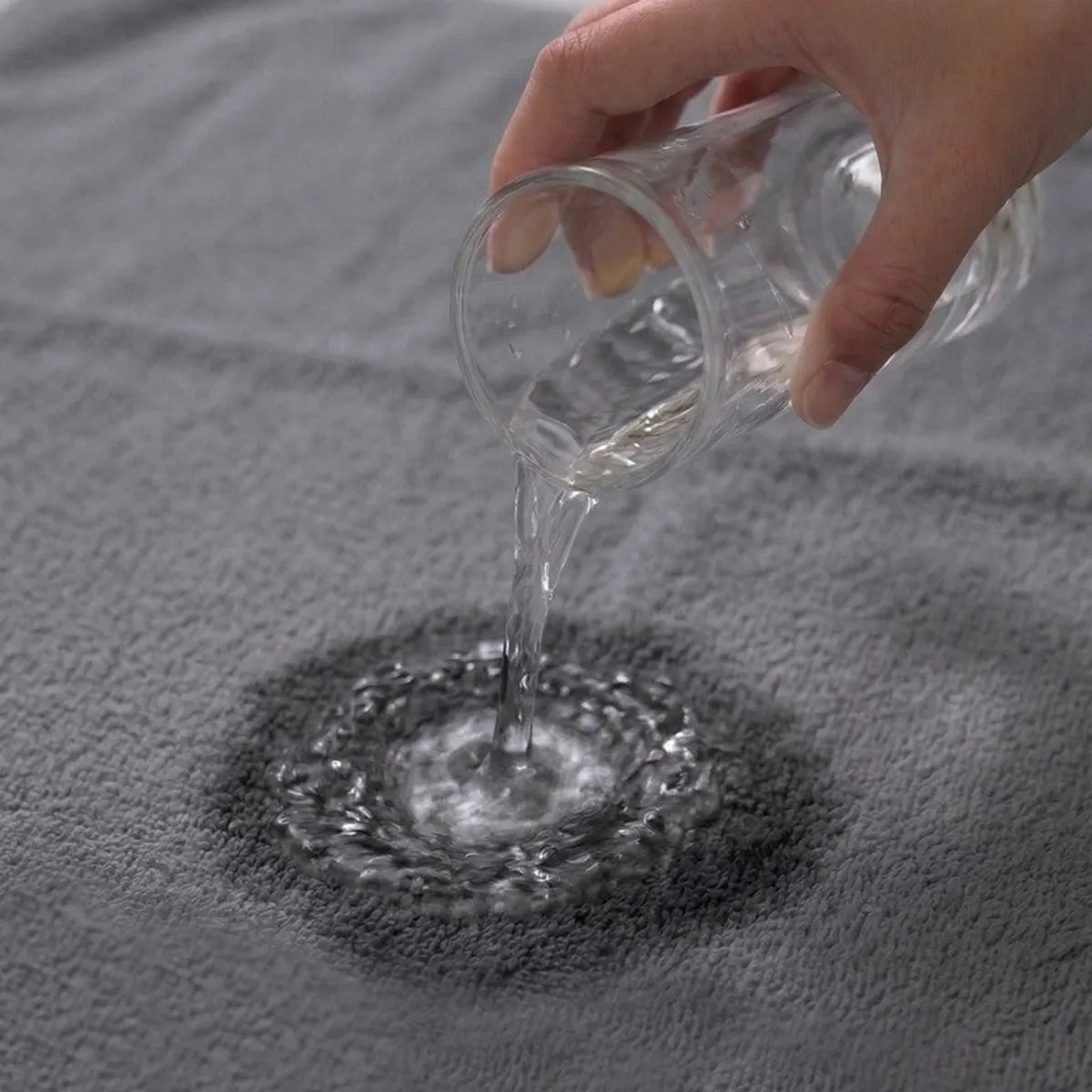 Water being poured onto a dark grey towel surface