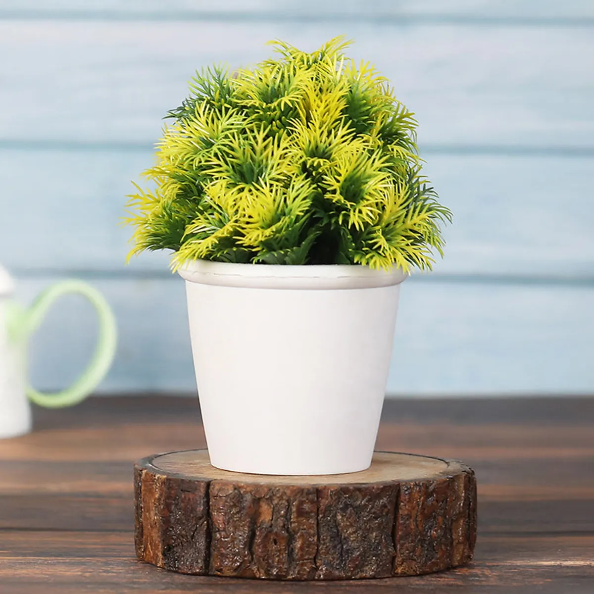 Yellow-green artificial plant in a white pot displayed on a wooden riser