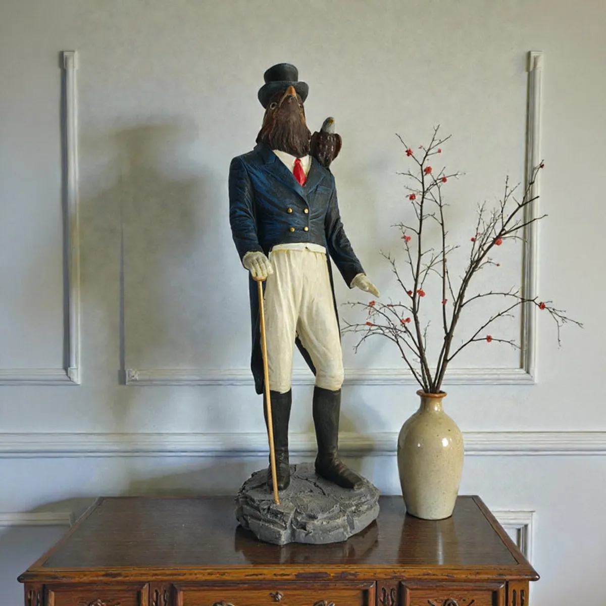 Rooster gentleman showpiece styled on a wooden cabinet beside a tall vase