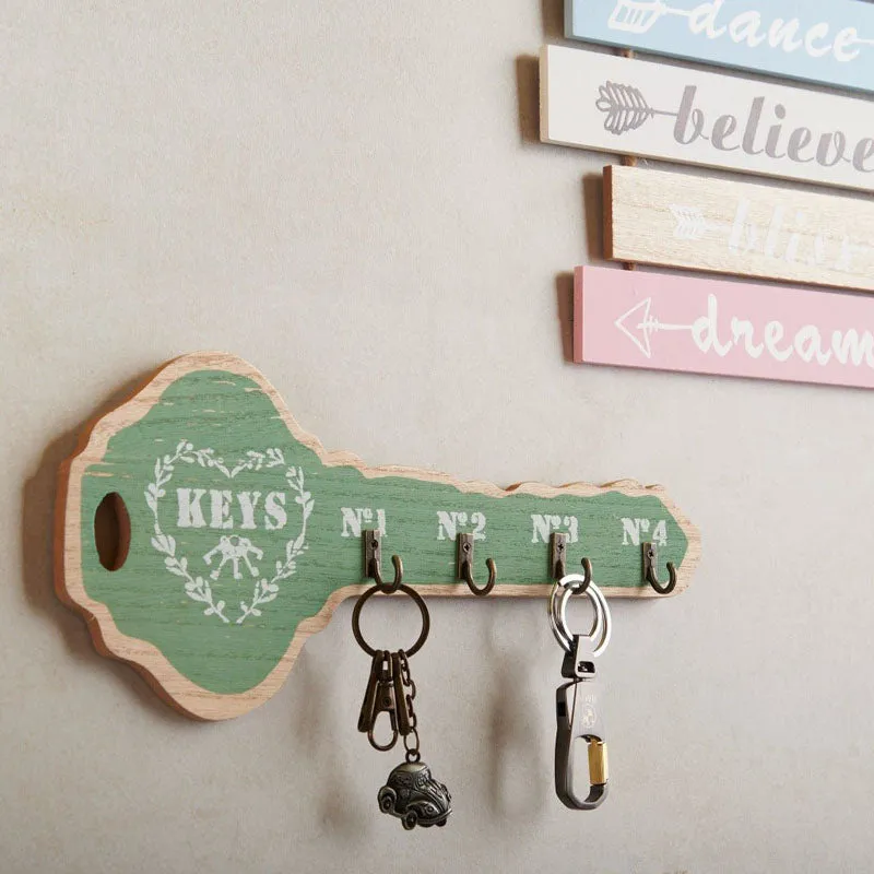 Green key holder mounted on a wall with keys hanging from the hooks