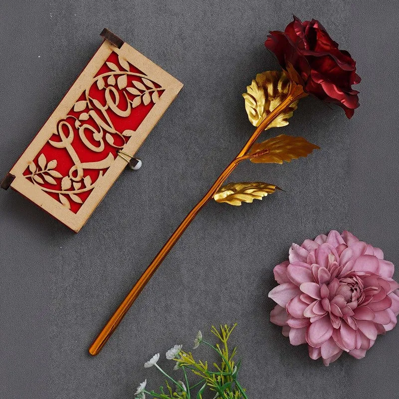Closed love-themed rectangular gift box beside a red rose with gold leaves