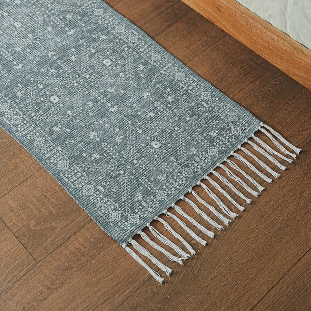 Corner detail of blue runner rug with white fringe and ethnic pattern