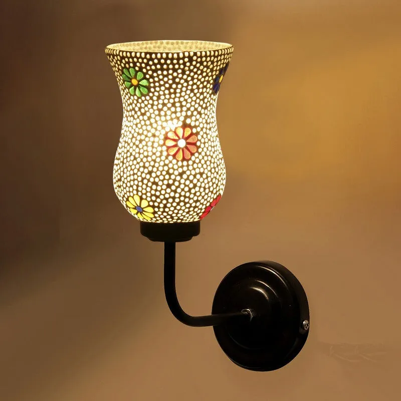 Close view of lit mosaic glass wall lamp with floral accents and black iron mount