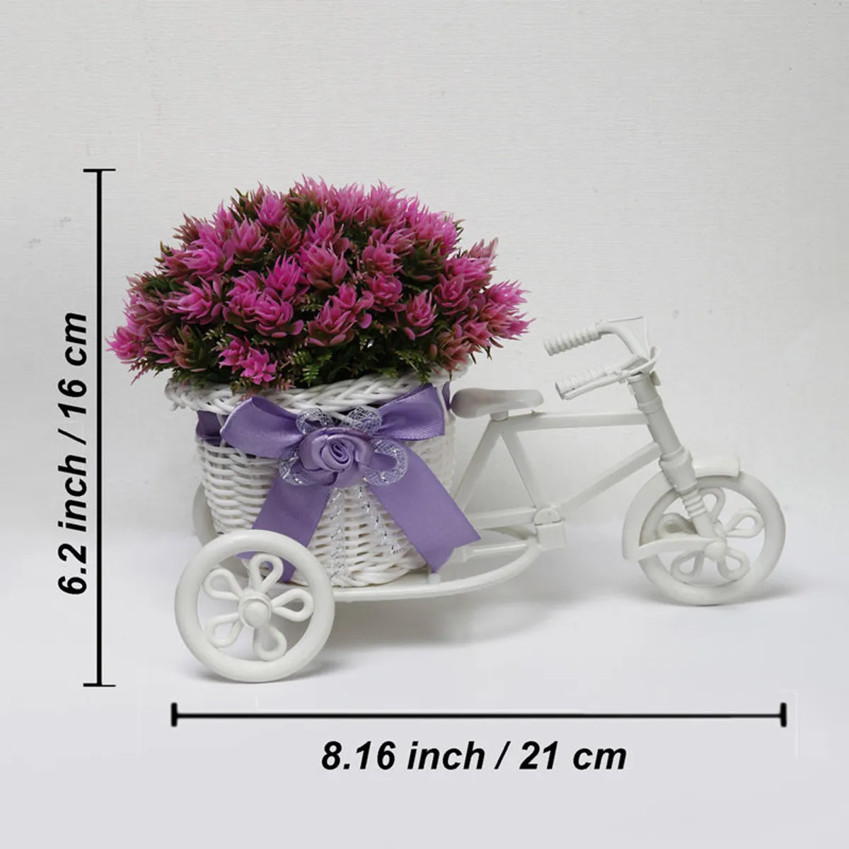 Pink artificial flower plant in a white mini cycle rickshaw pot with purple ribbon
