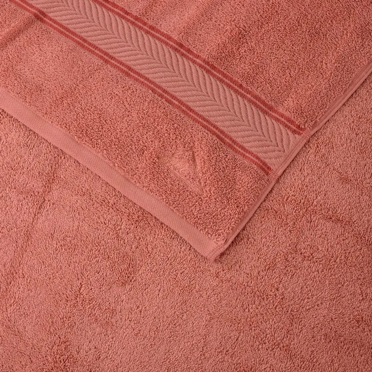 Close-up of the peach towel's textured pile and raised geometric border.