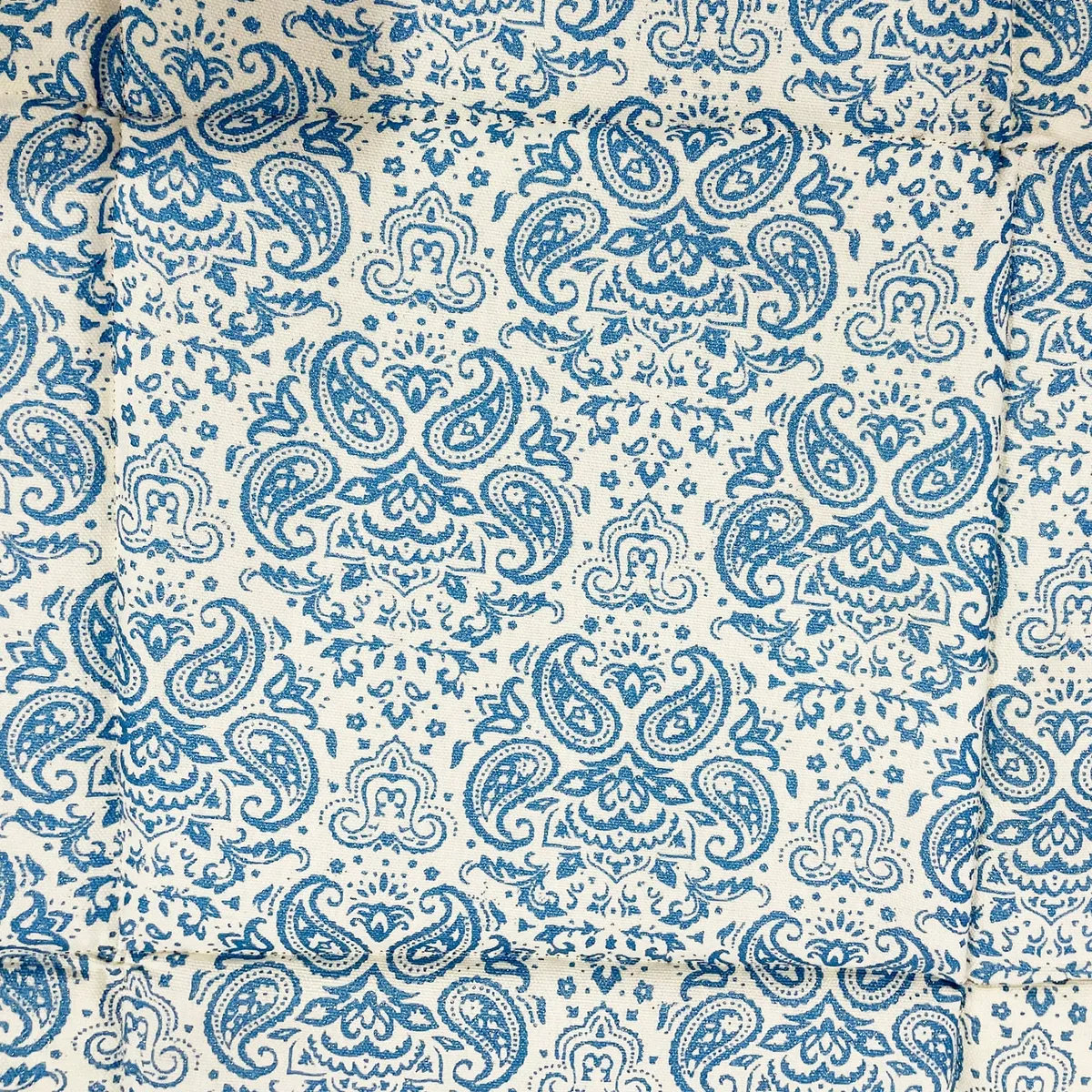 Close-up of blue paisley pattern on off-white cotton fabric