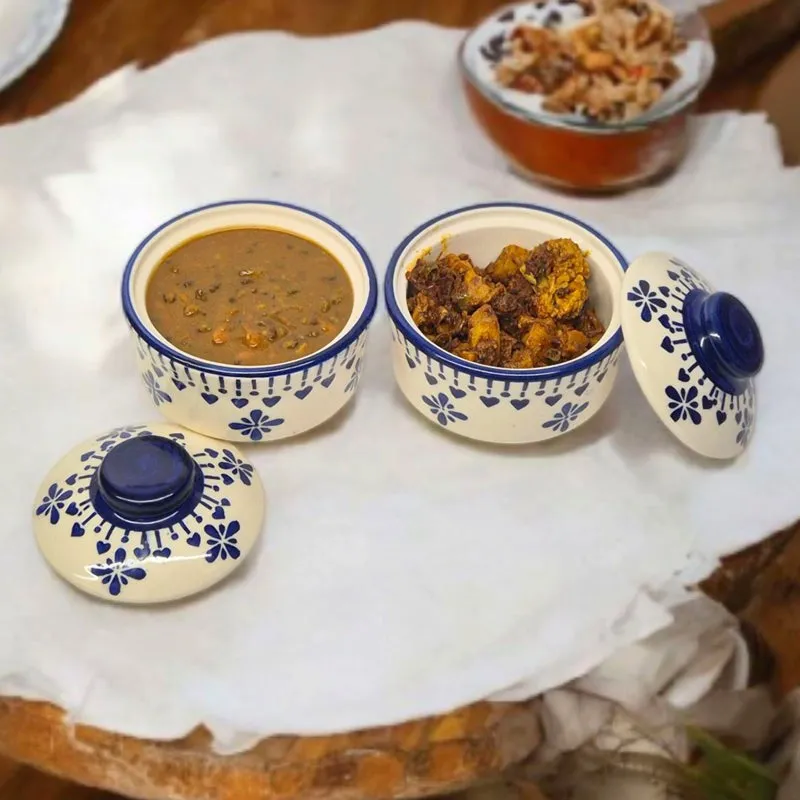 Two patterned ceramic serving bowls with lids, one filled with curry
