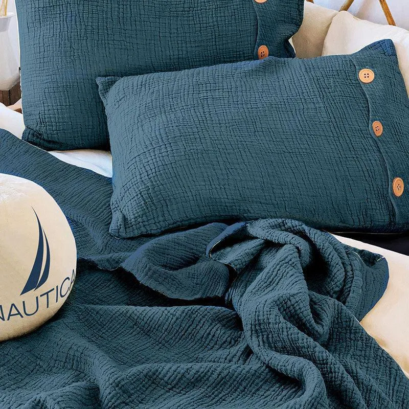 Close view of navy blue textured bedding and matching pillow covers with wooden buttons