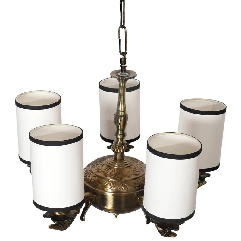 Top view of antique gold chandelier with five white cylindrical shades