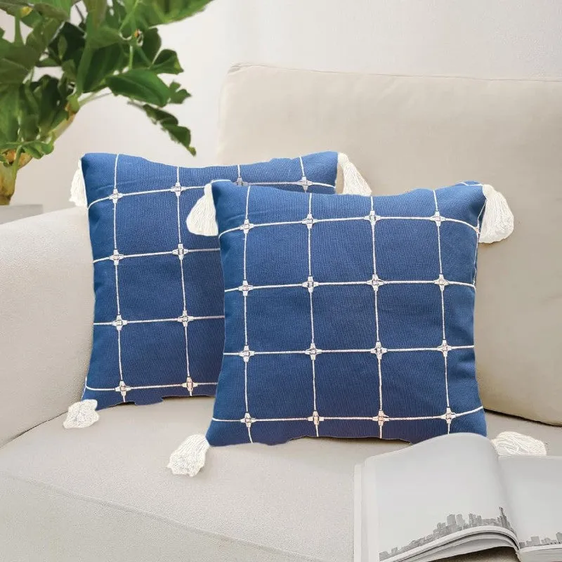 Two blue checked cushion covers with white tassels on a beige armchair