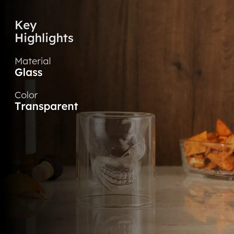 Transparent skull shot glass styled with a dark drink and bar accessories.