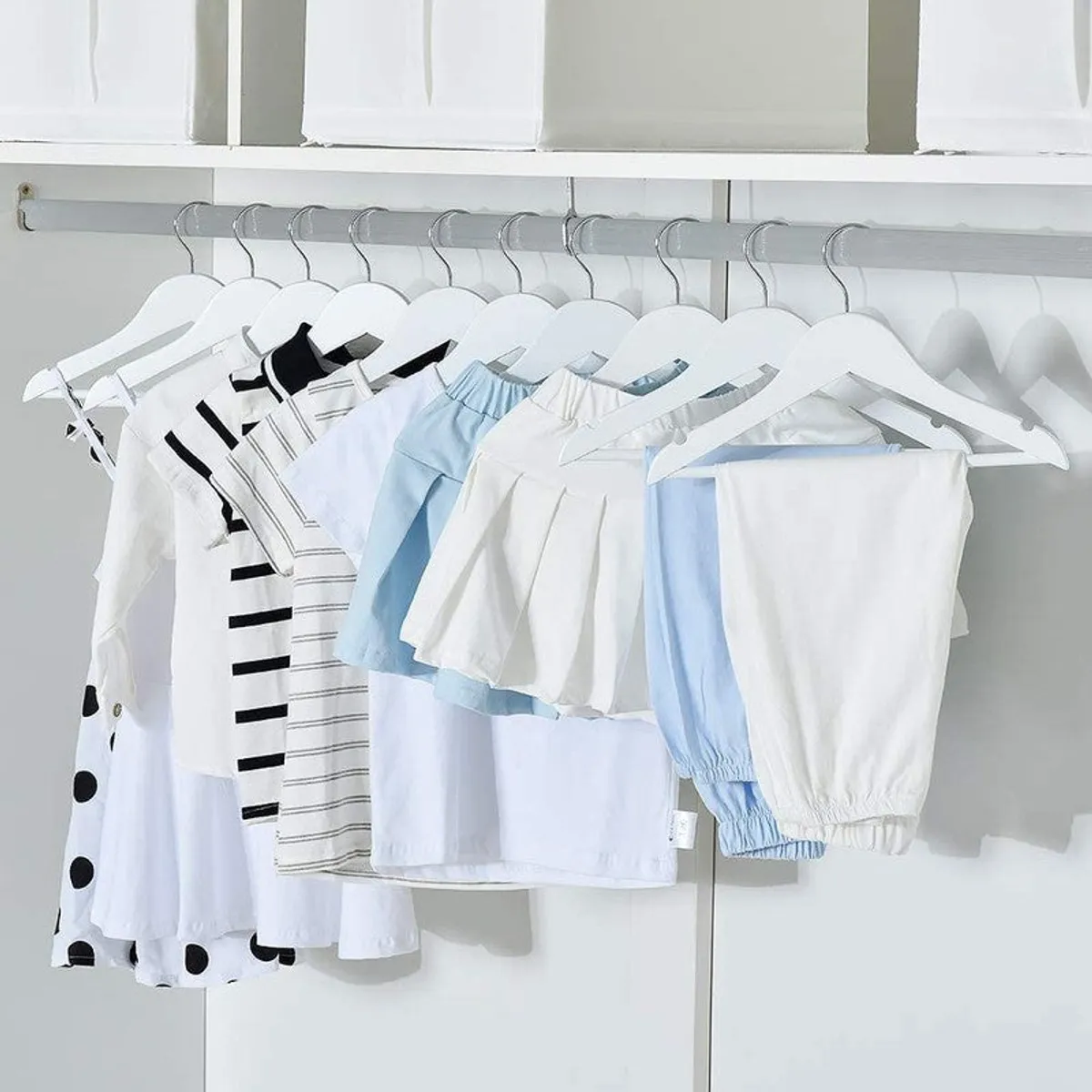 White hangers displaying children’s clothing on a wardrobe rail