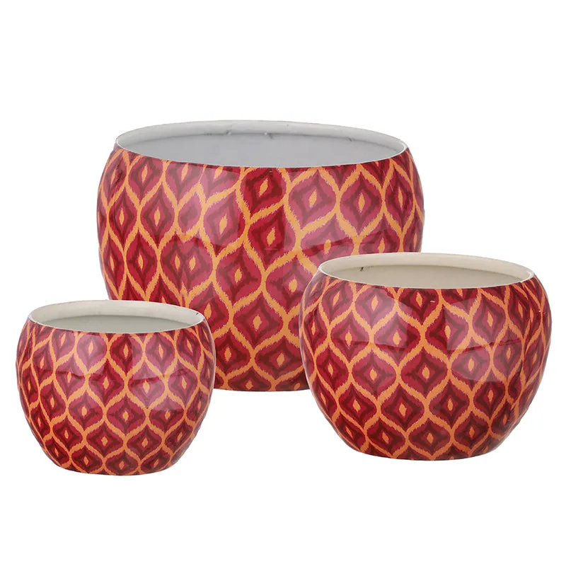 Three maroon round planters with geometric pattern on a white background