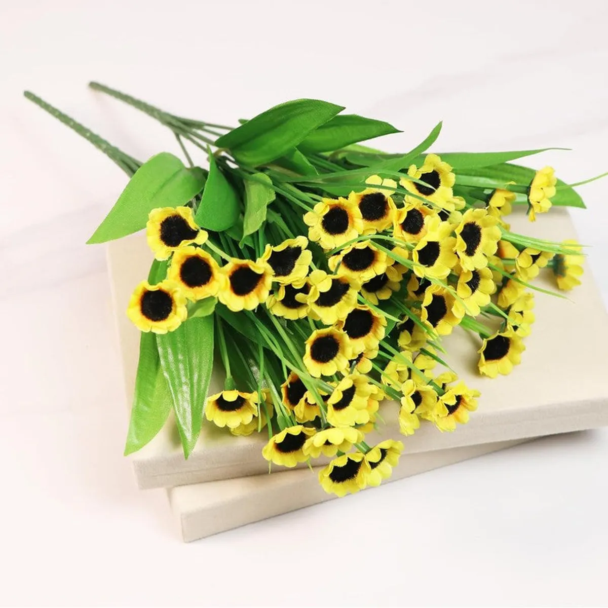 Artificial yellow sunflower stems laid across closed books.