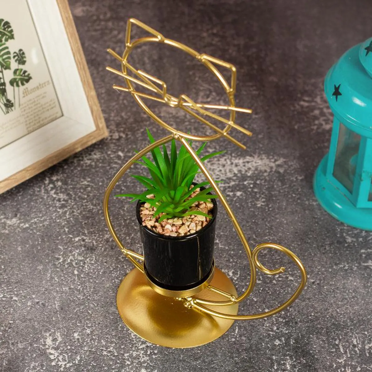Angled view of gold cat-shaped metal planter with black pot and green plant