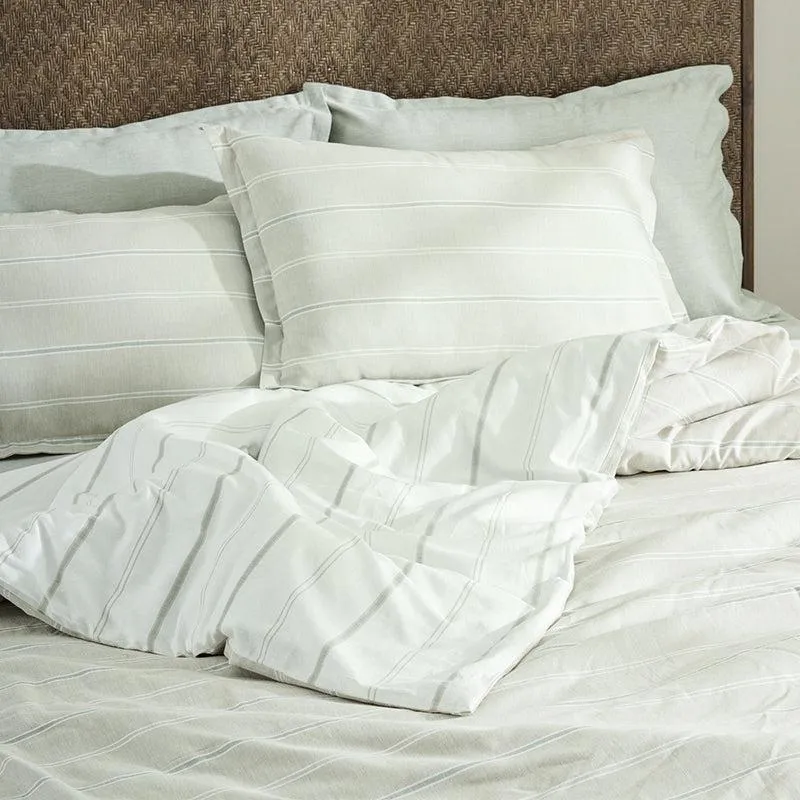 Beige striped duvet cover and matching pillow covers arranged on a bed.