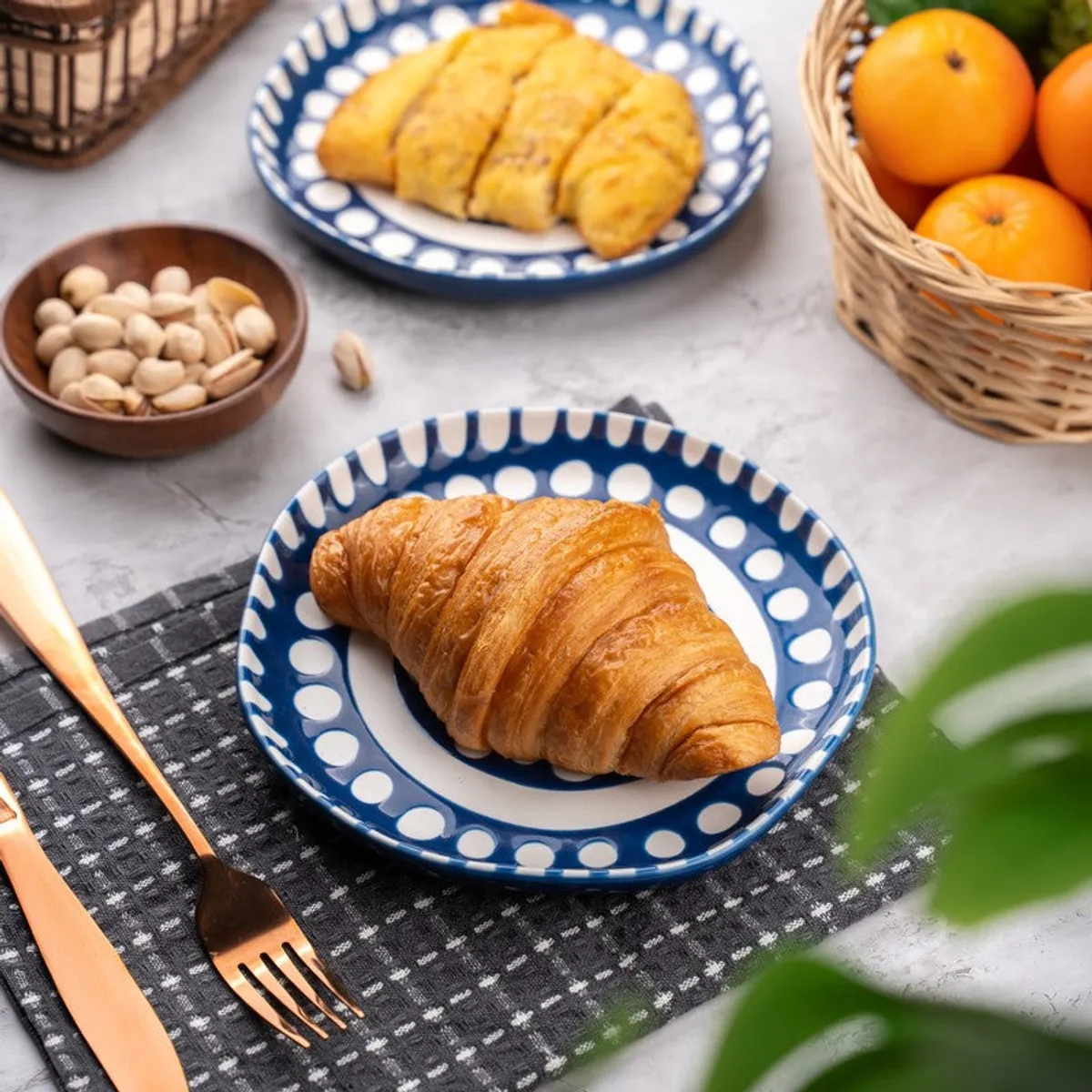 Blue and white patterned plate holding a croissant with fruit and snacks nearby