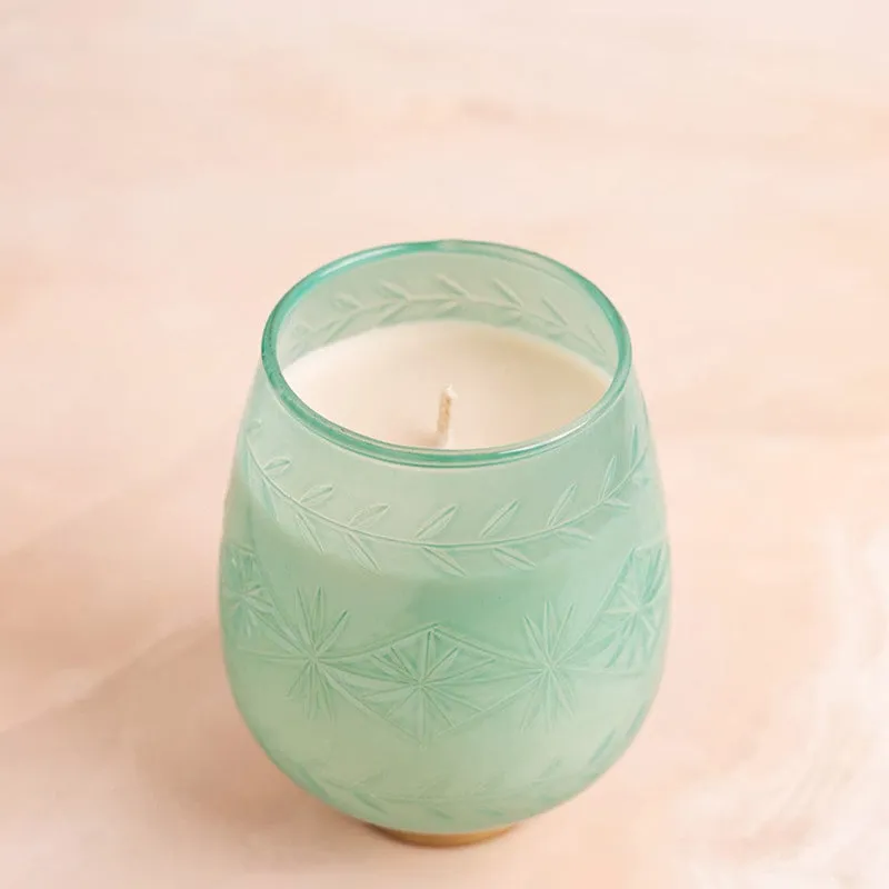 Unlit green candle in a frosted patterned glass holder with a gold-toned base