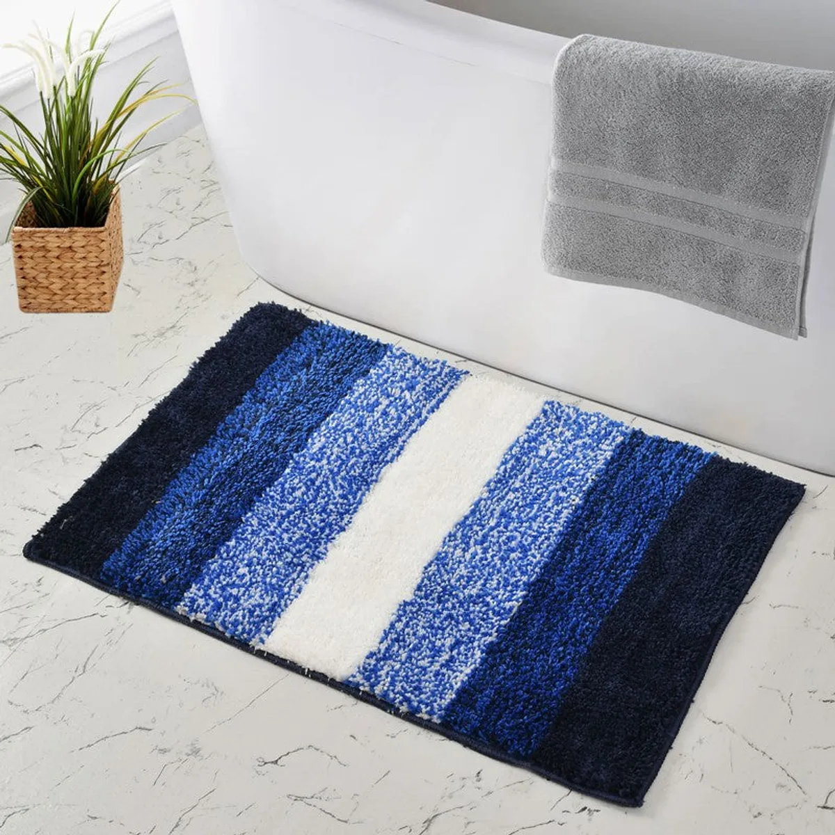 Blue striped bath mat beside a bathtub on a light floor