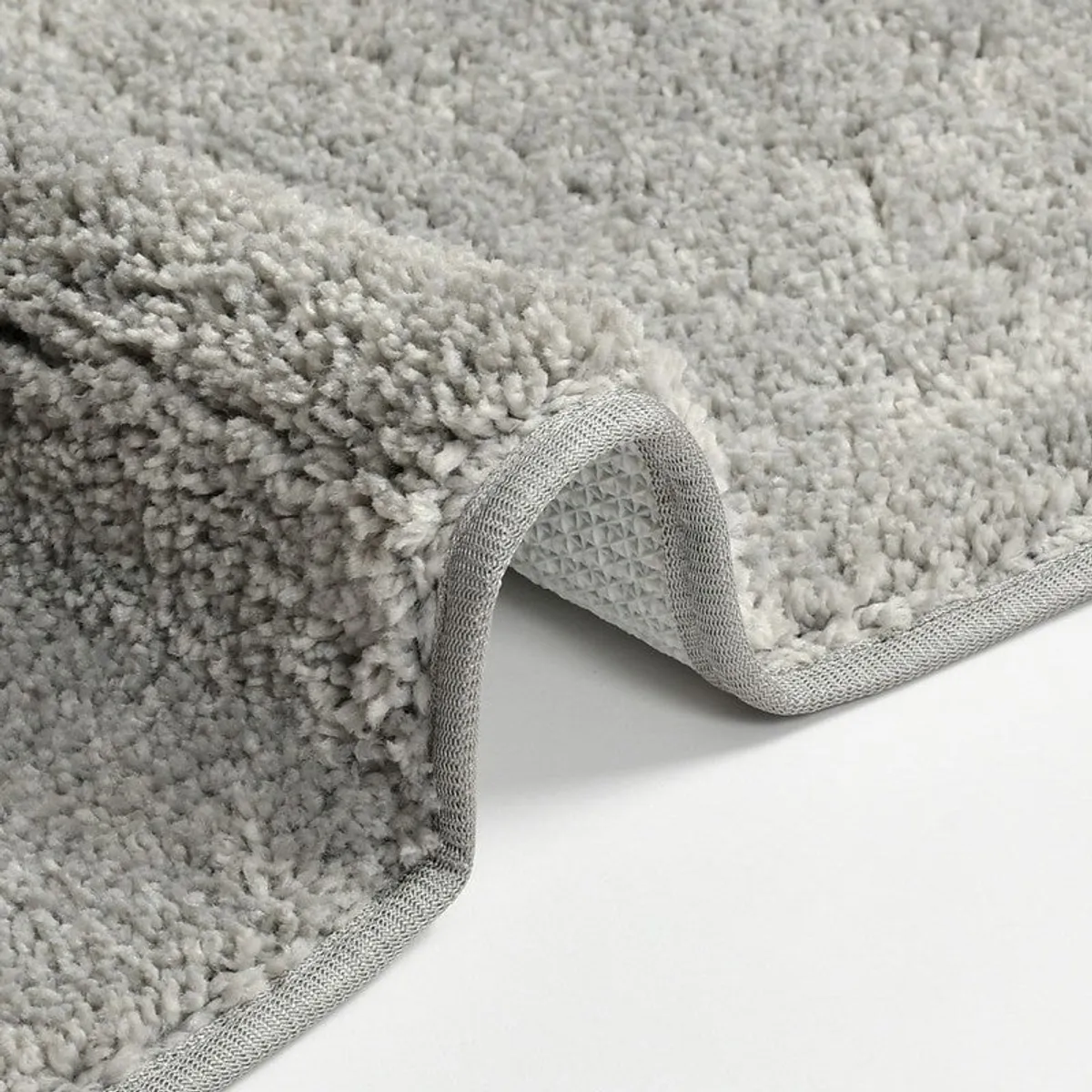 Close-up of grey bath mat edge and textured backing