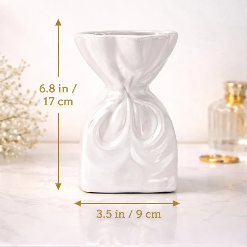 White sculptural vase shown front-facing with measurement arrows in a styled setting