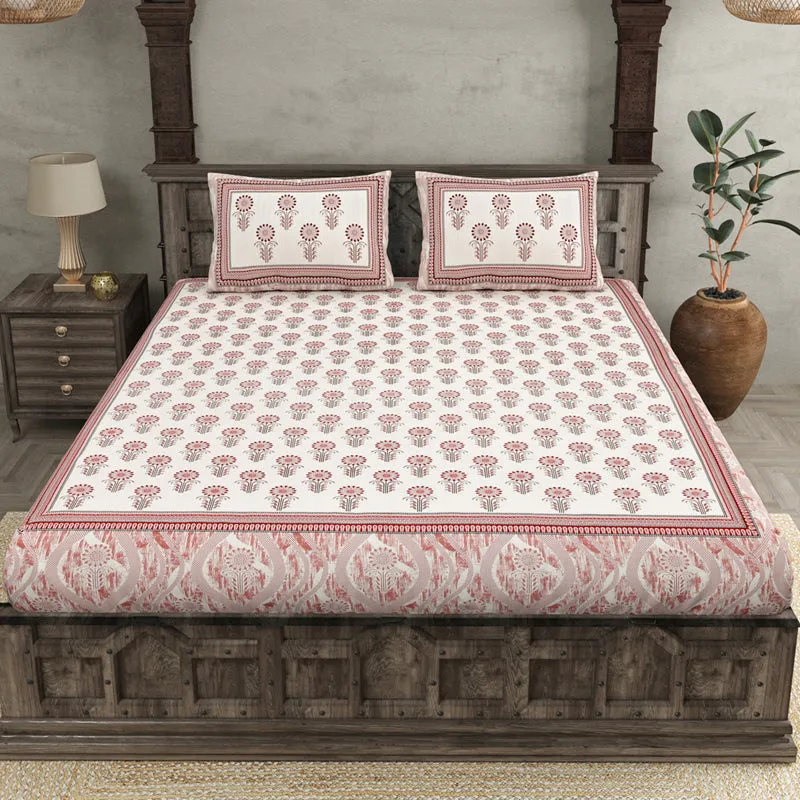 Pink and white floral bedsheet with two matching pillow covers on a wooden bed