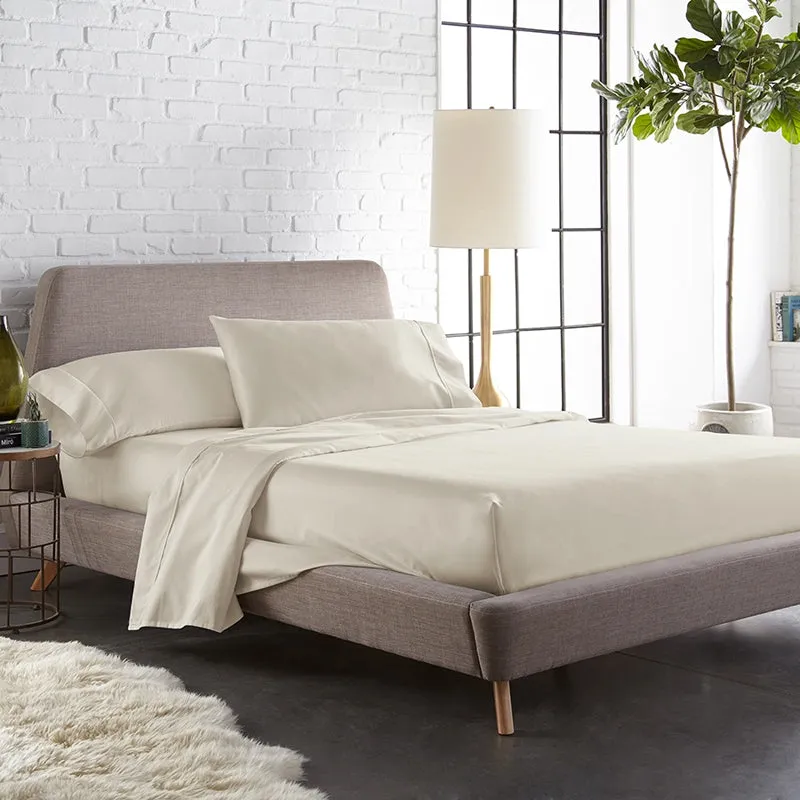 Beige fitted bedsheet styled on a modern bed in a bright bedroom