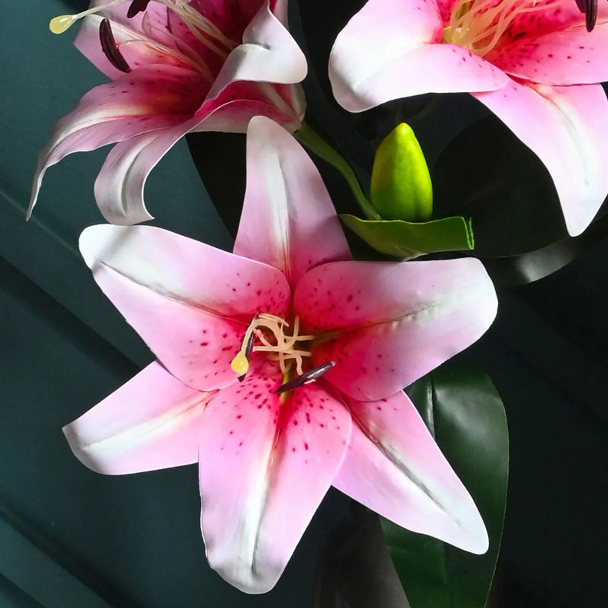 Close-up of pink and white artificial lily blooms with green leaves