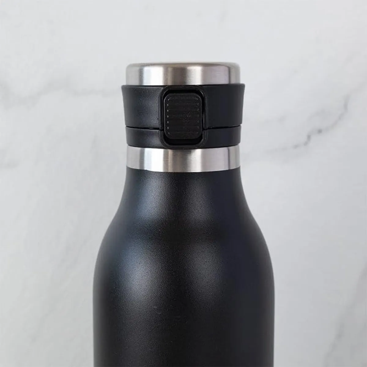 Close-up of the black bottle showing its matte finish and secure lid