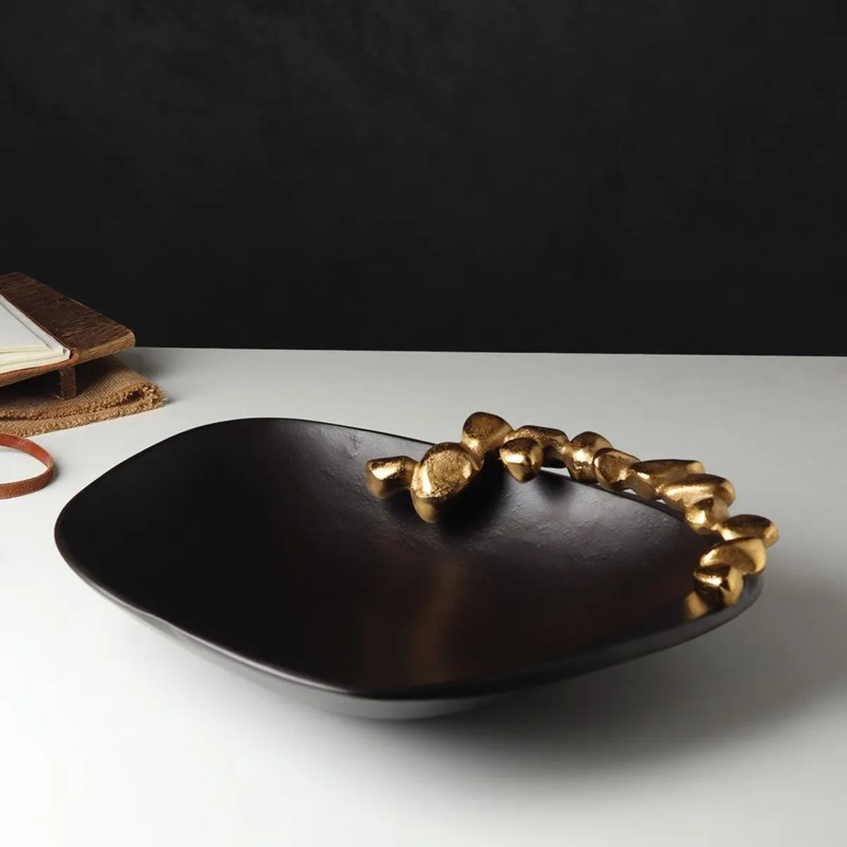 Angled view of a black bowl with an irregular gold rim and matte surface.
