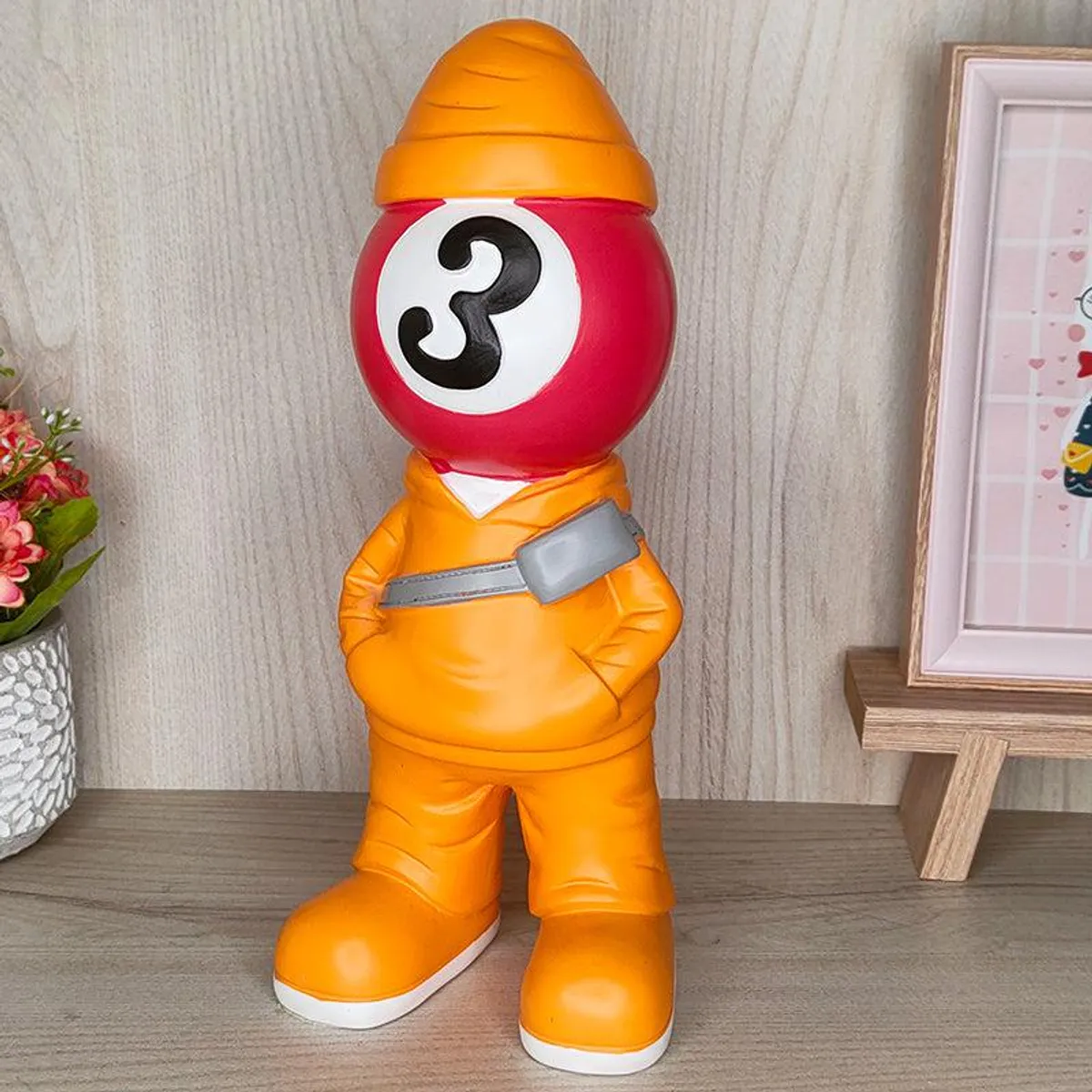 Angled front view of the yellow-orange figurine showpiece on a wooden surface.