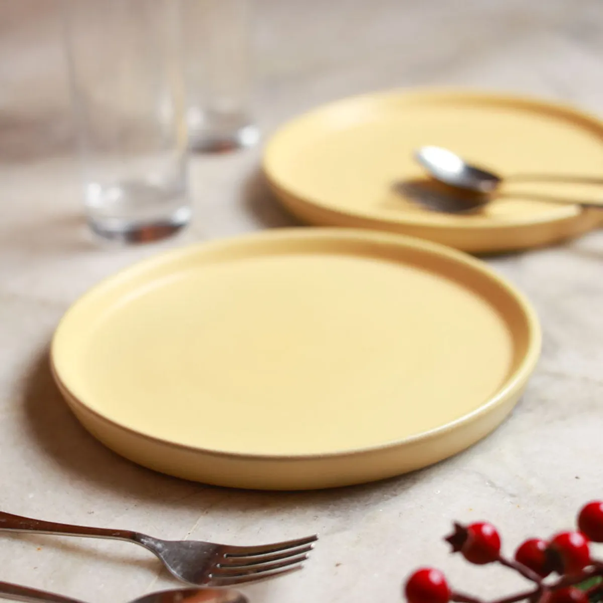 Yellow ceramic dinner plate shown at an angle with cutlery