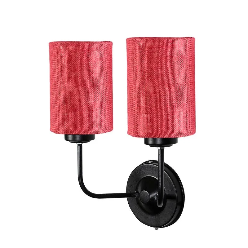 Angled view of pink twin jute wall lamp with black iron wall mount