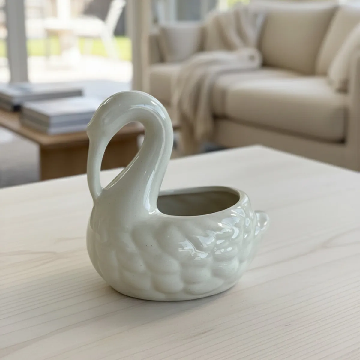 White swan-shaped vase displayed on a light coffee table in a living room