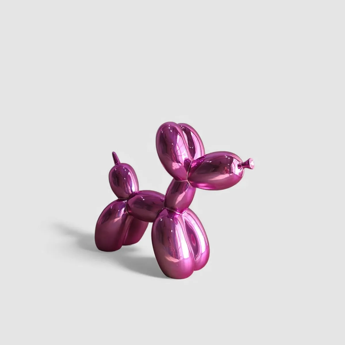 Angled view of a metallic pink balloon dog showpiece on a plain light background.