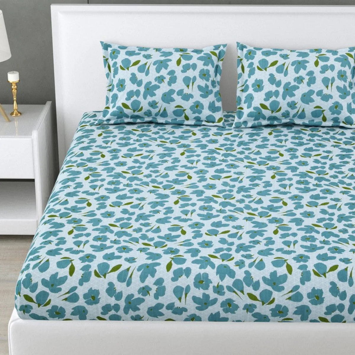 Close view of blue floral bedsheet spread across a white bed