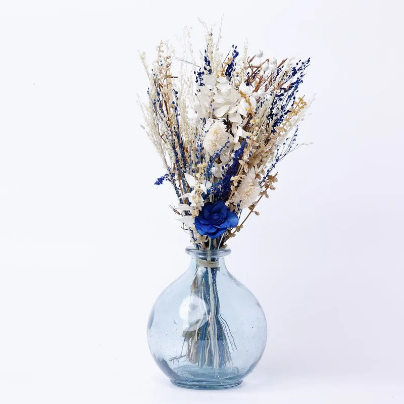 Multicolour dried flowers arranged in a pale blue glass vase