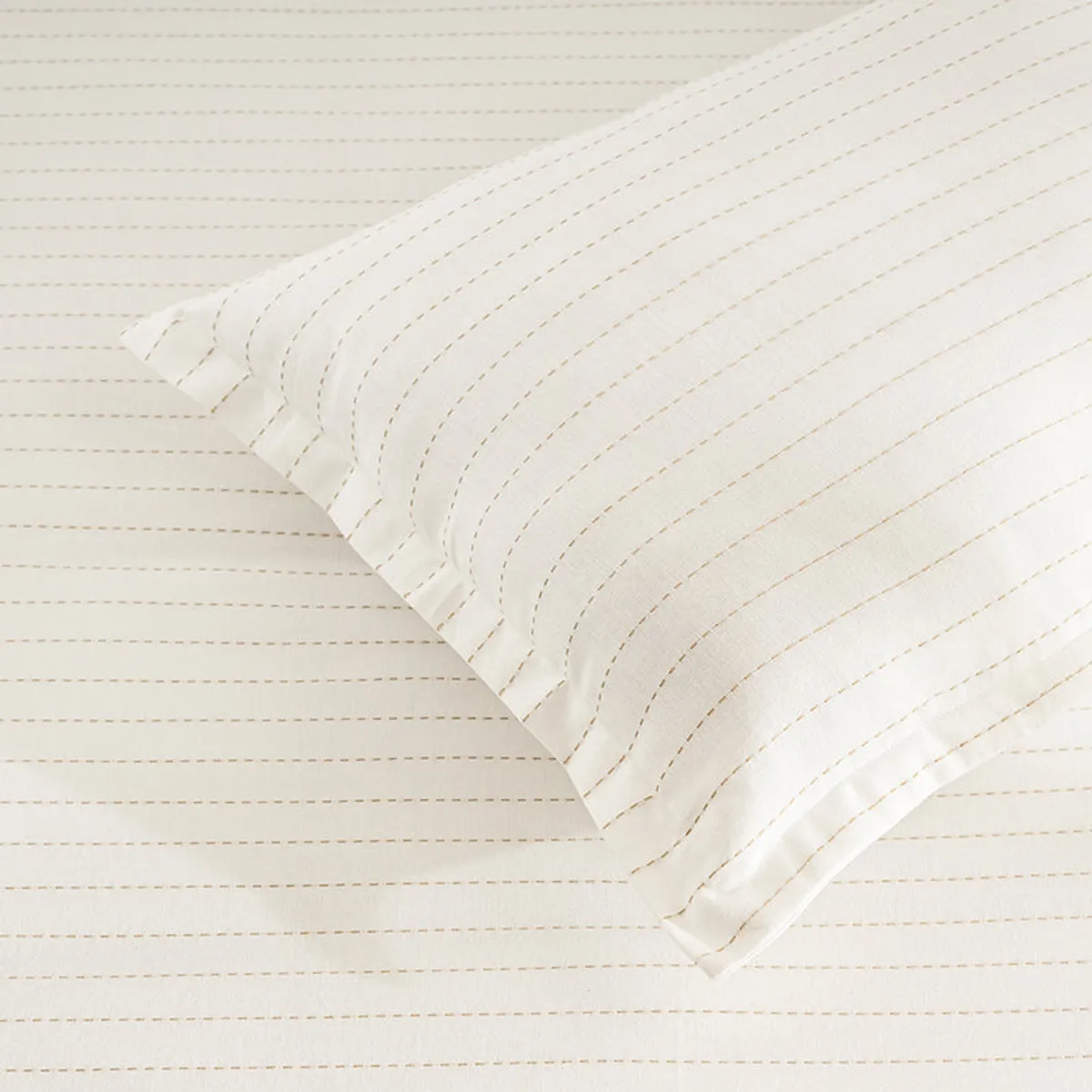 Close-up of white bedding with subtle dashed stripes