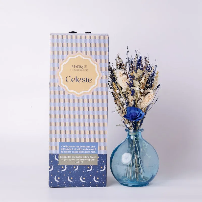 Boxed dried flower arrangement placed beside a blue glass vase