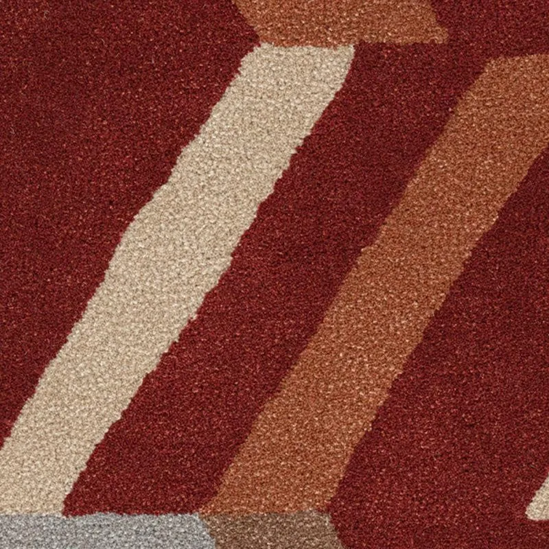 Close-up of geometric carpet pattern in maroon, beige and rust tones