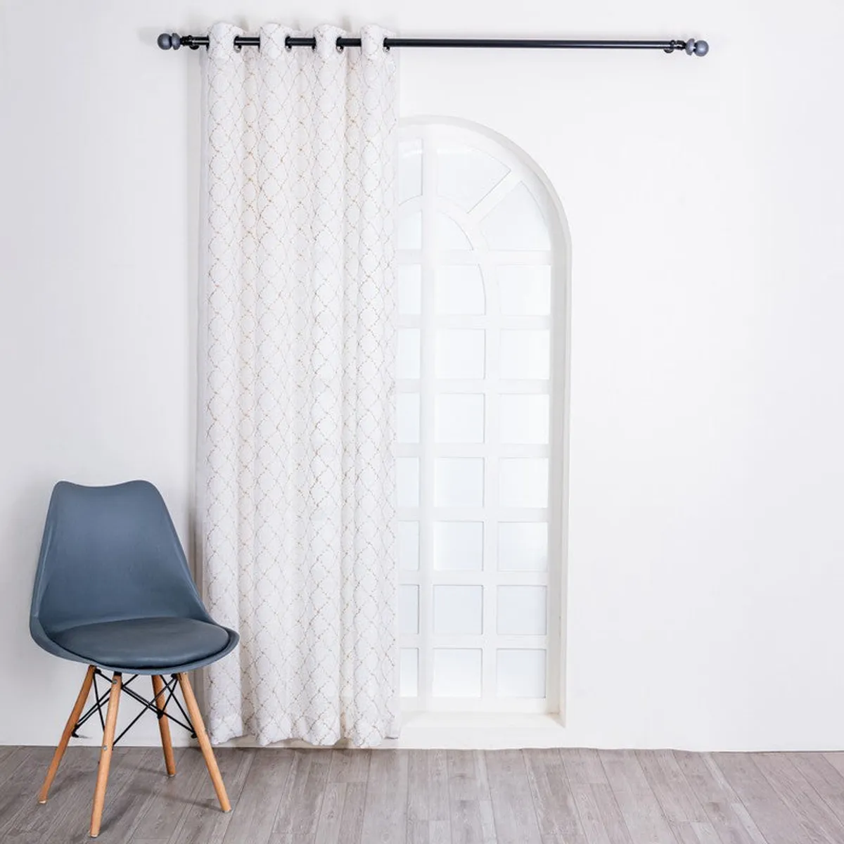 White and gold embroidered sheer curtain styled across a tall arched doorway.
