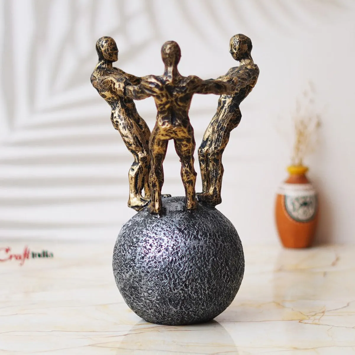 Rear view of gold-toned figurine circle on a textured grey sphere