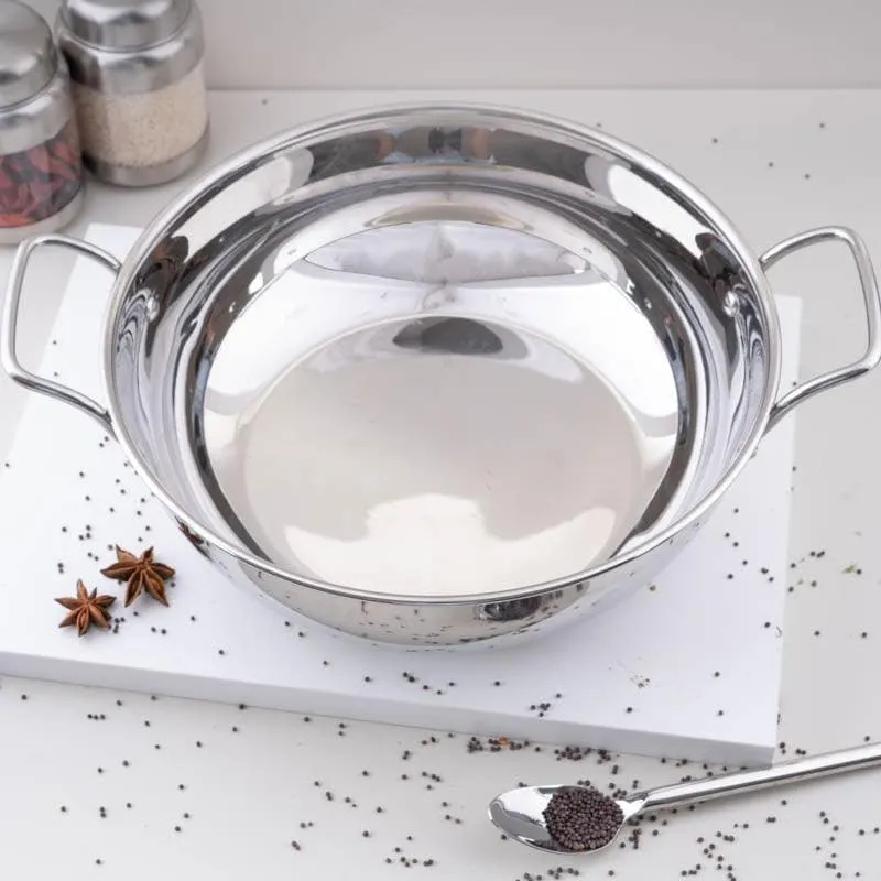 Glossy silver stainless steel kadhai with two handles on a white kitchen surface
